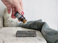 lavender essential being dropped onto a shower steamer lava stone that is set on a piece of marble with a green towel draped beside